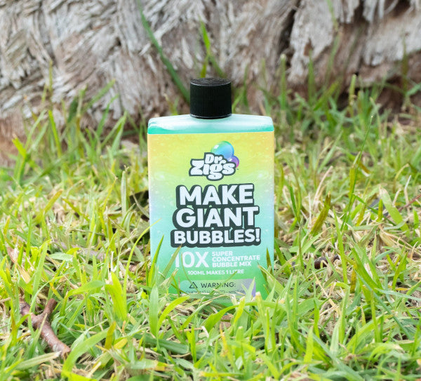 a flat rectangular shaped bottle of concentrated bubble liquid sits on the grass