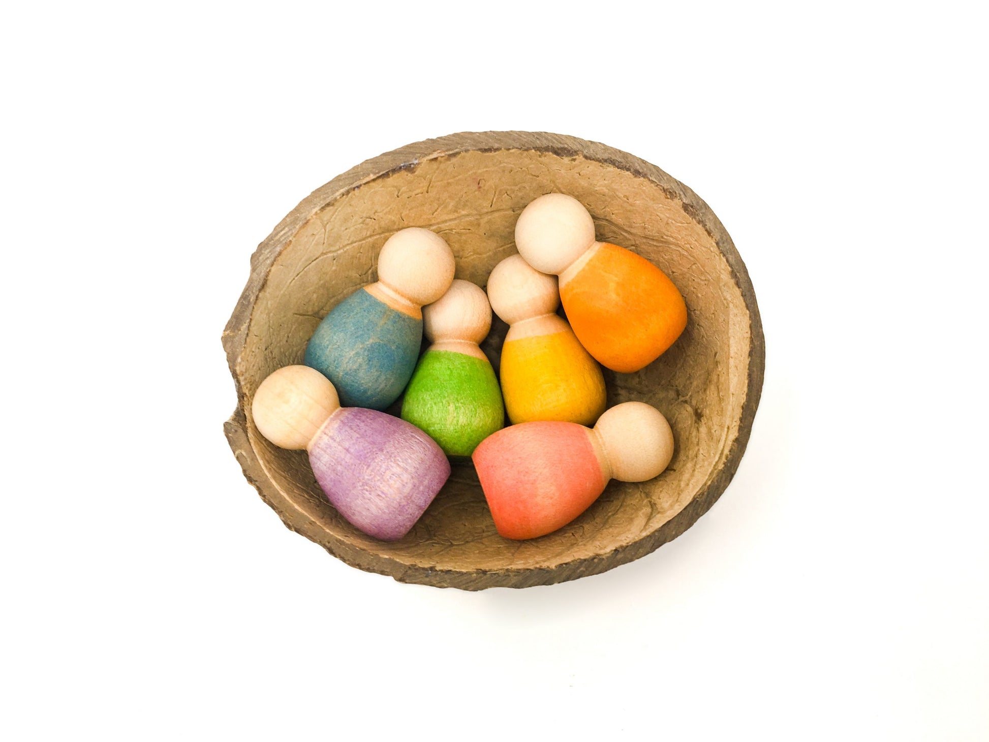 6 wooden babies nestled in a half coconut shell.  Each baby nin is painted a different rainbow colour.